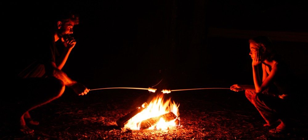 Image of two friends roasting marhmallows in the dark over a campfire at a tent campsite at Ginnie Springs in High Springs, FL